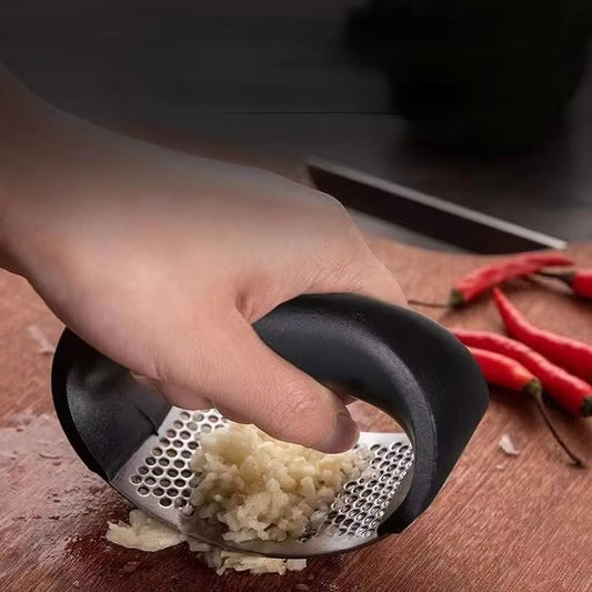 Easily pressing garlic cloves with stainless steel garlic mincer for effortless food prep.